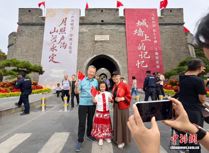 游客在宛平城城墙与国旗合影