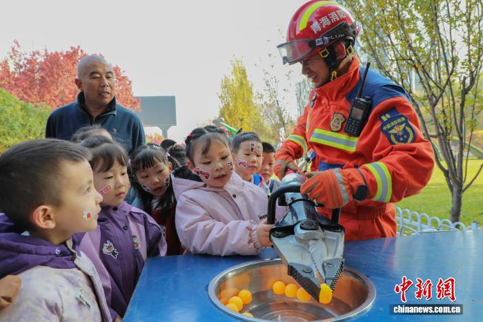 消防员协助小朋友体验使用液压剪扩钳夹乒乓球