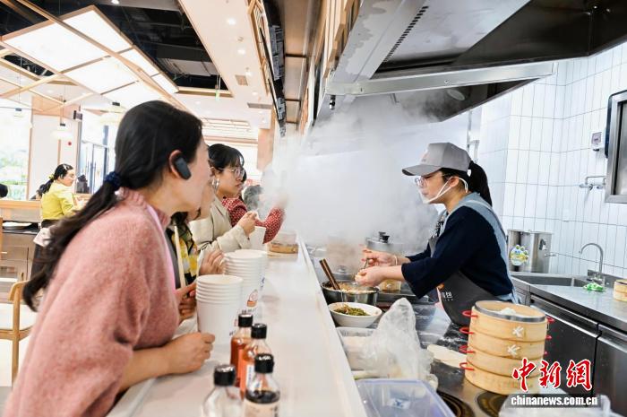 参观者与制作小笼包的妇女交流